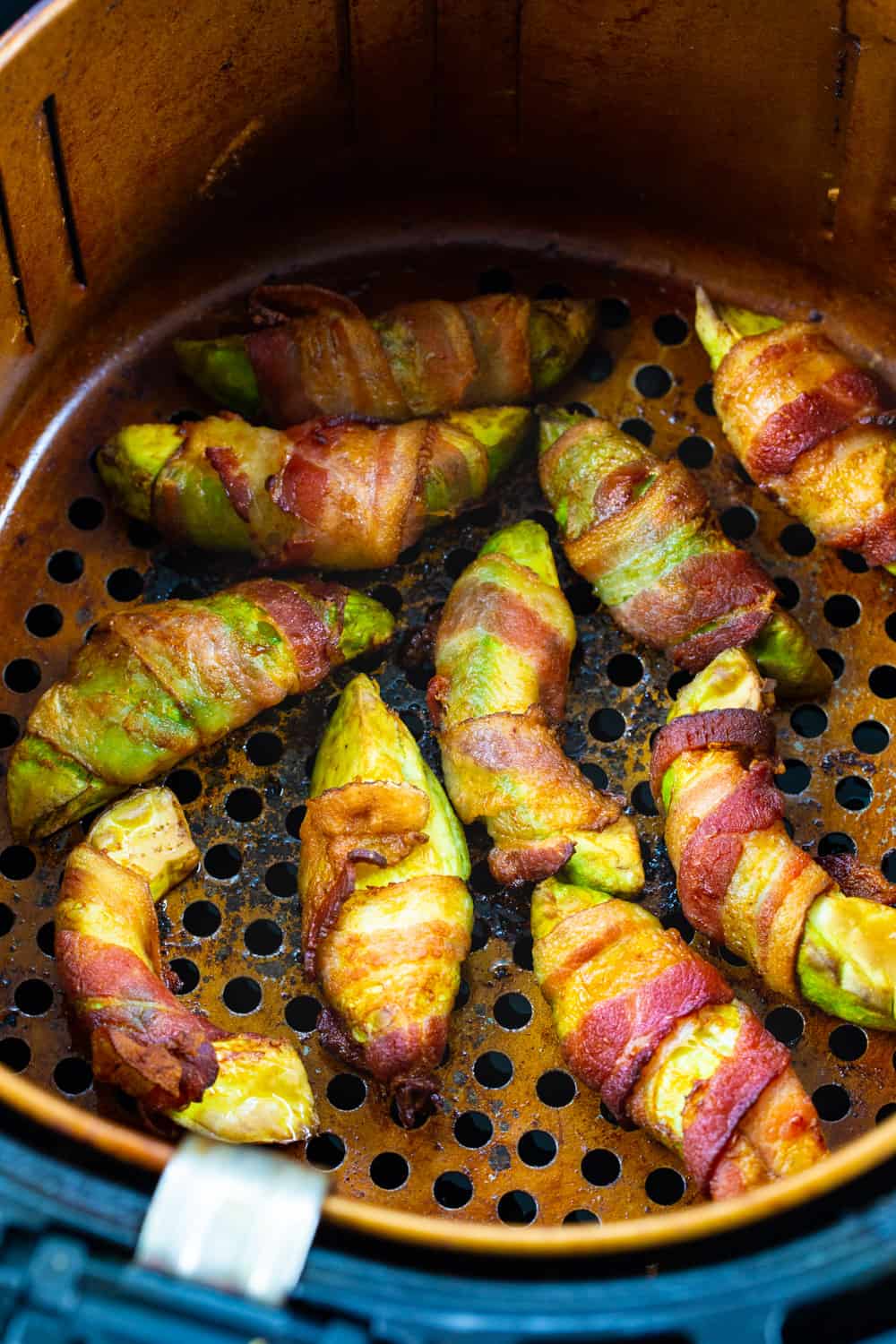 Bacon Wrapped Avocado Slices in air fryer basket.