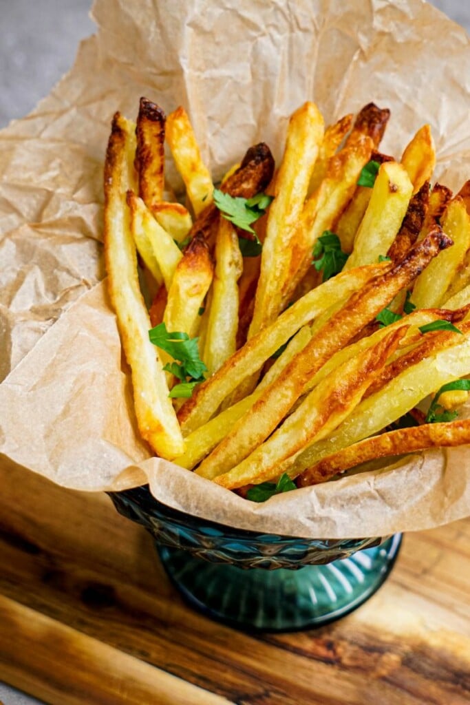 Cooked air fryer french fries in a bowl with parchment paper