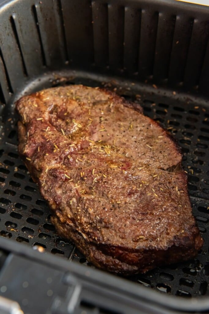 Closeup of cooked frozen steak in air fryer basket