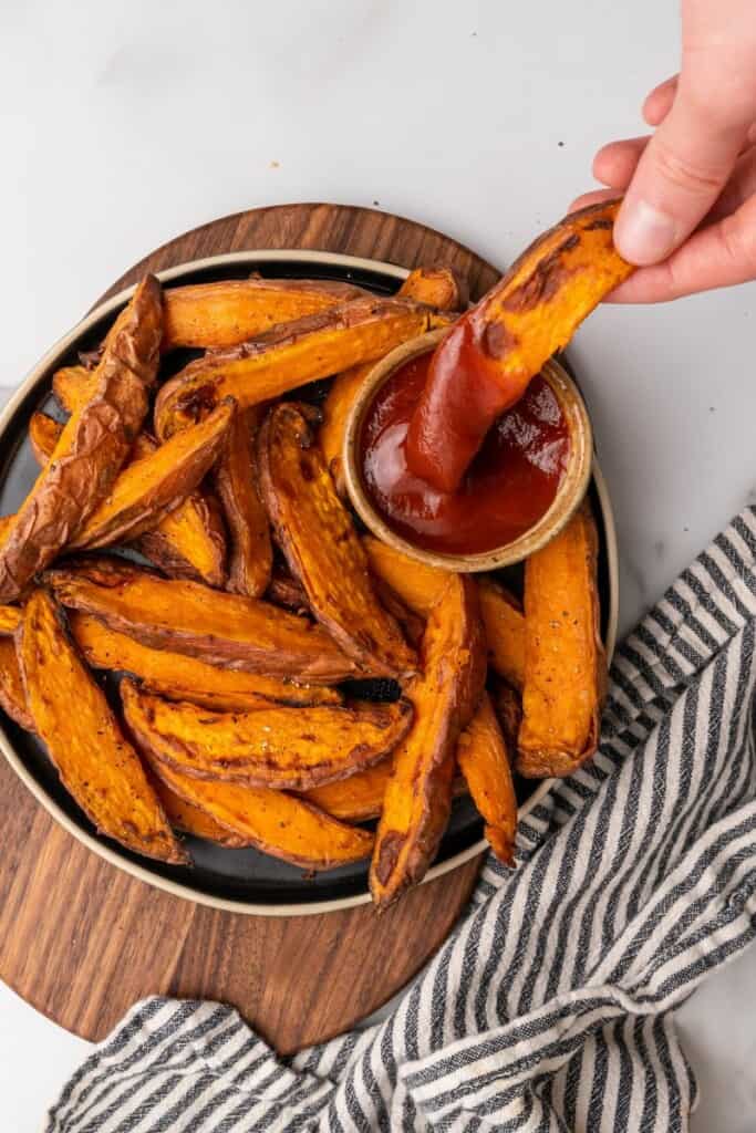 dipping sweet potato wedge into ketchup