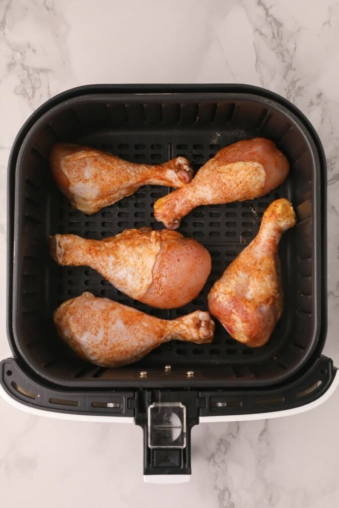 Raw chicken drumsticks in air fryer basket