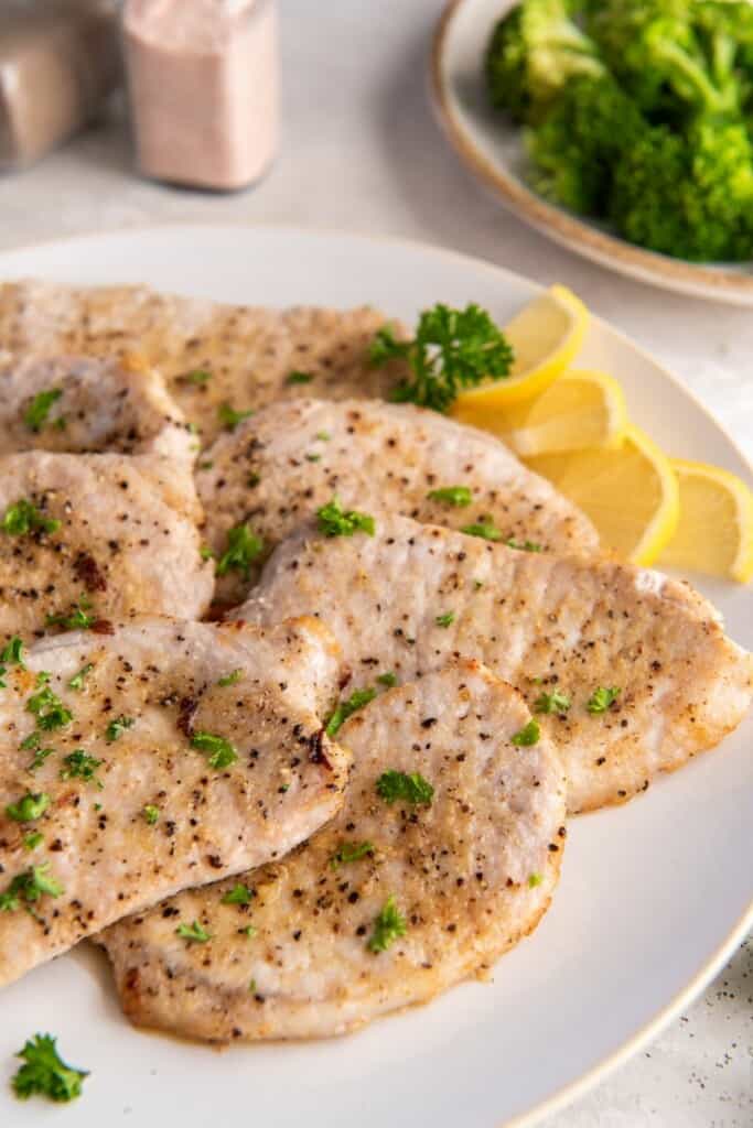 pork chops on a white plate with lemon slices