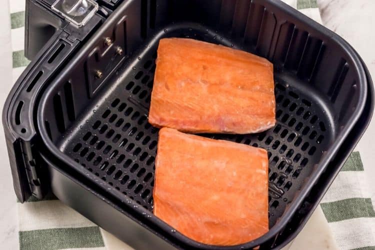 Raw salmon in an air fryer skin-side down.