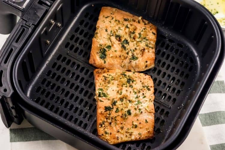 Raw salmon in the air fryer with garlic butter mixture on top