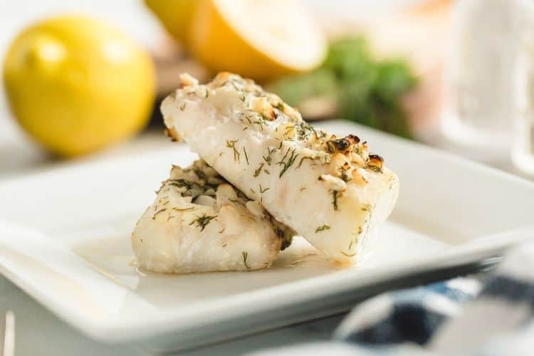 Air Fryer Cod with no breading on a white plate with ingredients in the background