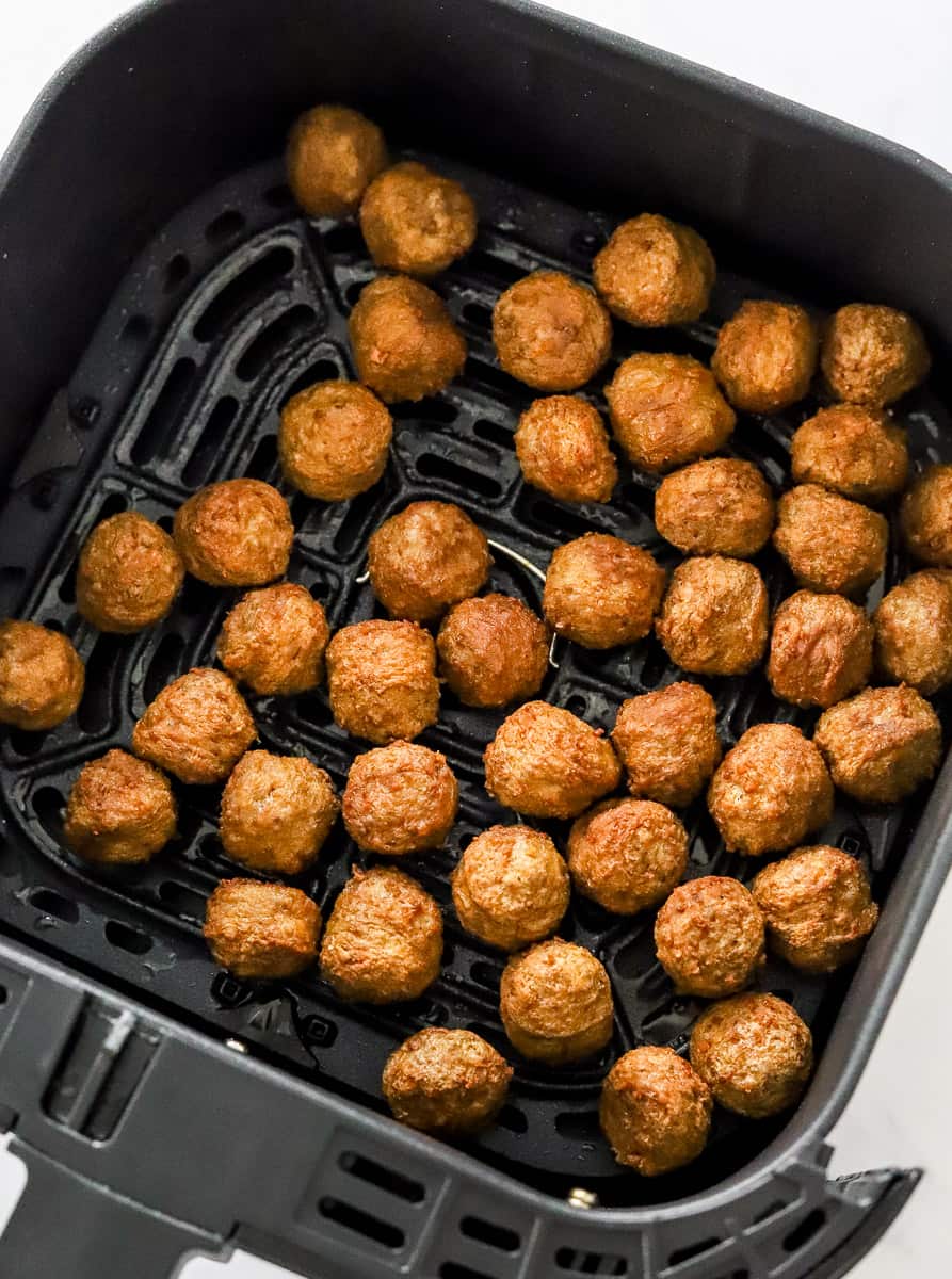 Cooked turkey meatballs in a black air fryer basket.