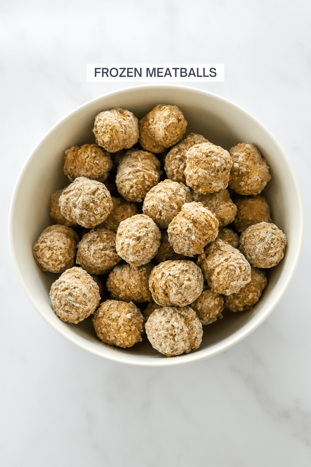 Frozen meatballs in a round white bowl with a label for the meatballs above them.